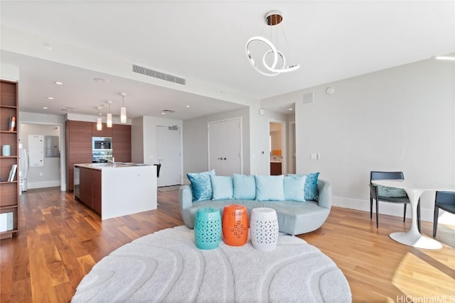 living room with light hardwood / wood-style floors and a notable chandelier