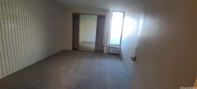 unfurnished bedroom featuring carpet, an AC wall unit, and a closet