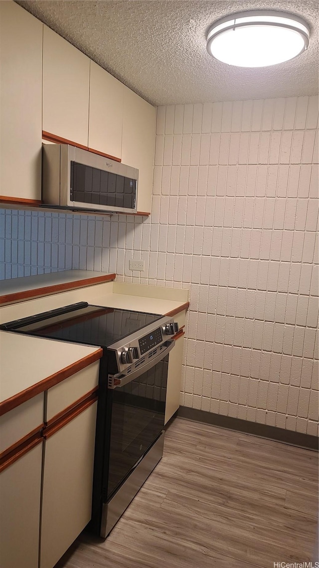 855 Makahiki Way Unit 207, Honolulu, HI 96826 - kitchen featuring appliances with stainless steel finishes, light wood finished floors, tile walls, a textured ceiling, and light countertops