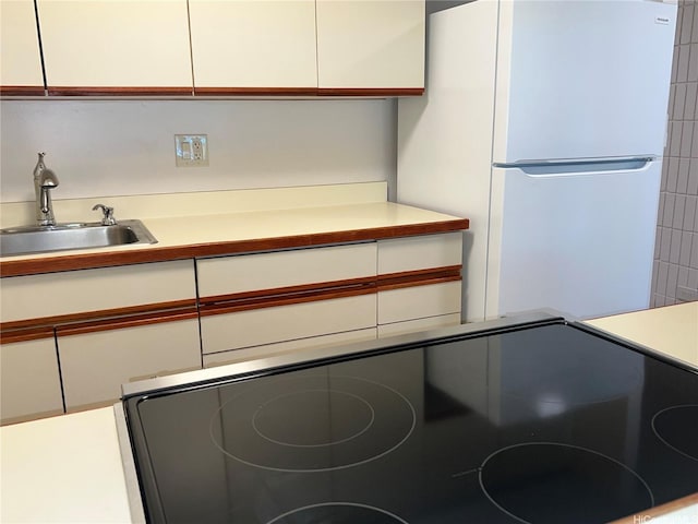 855 Makahiki Way Unit 207, Honolulu, HI 96826 - kitchen with freestanding refrigerator, a sink, light countertops, white cabinets, and black range with electric stovetop