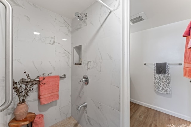 bathroom with wood-type flooring and tiled shower