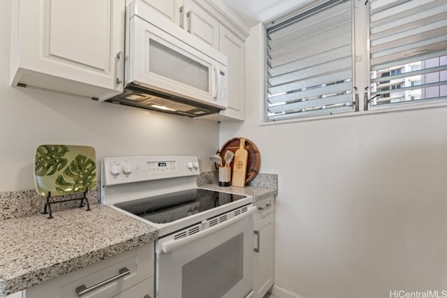 kitchen with light stone countertops, white appliances, white cabinetry, and a healthy amount of sunlight