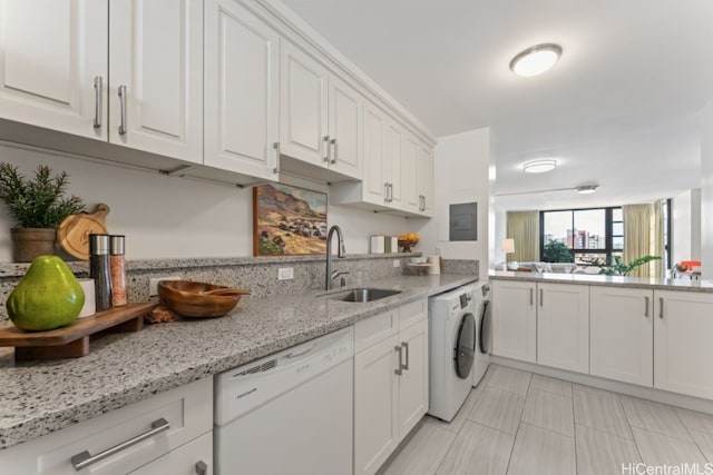 kitchen with white cabinets, light stone counters, washer and clothes dryer, sink, and dishwasher