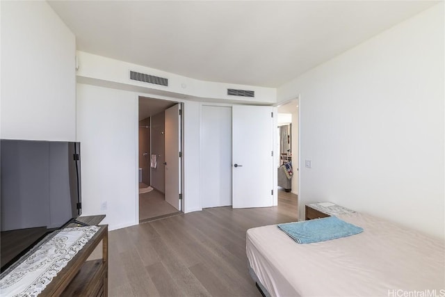 bedroom with dark hardwood / wood-style floors, a closet, and ensuite bath