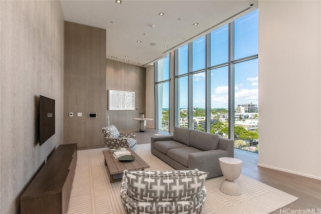 living room featuring plenty of natural light, wood-type flooring, a high ceiling, and a wall of windows