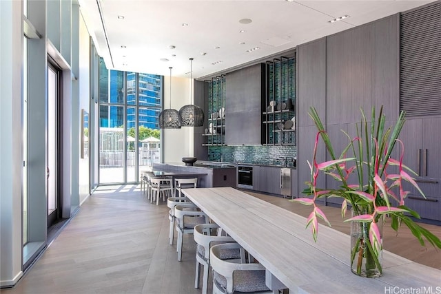 interior space featuring pendant lighting, a healthy amount of sunlight, a wall of windows, and tasteful backsplash