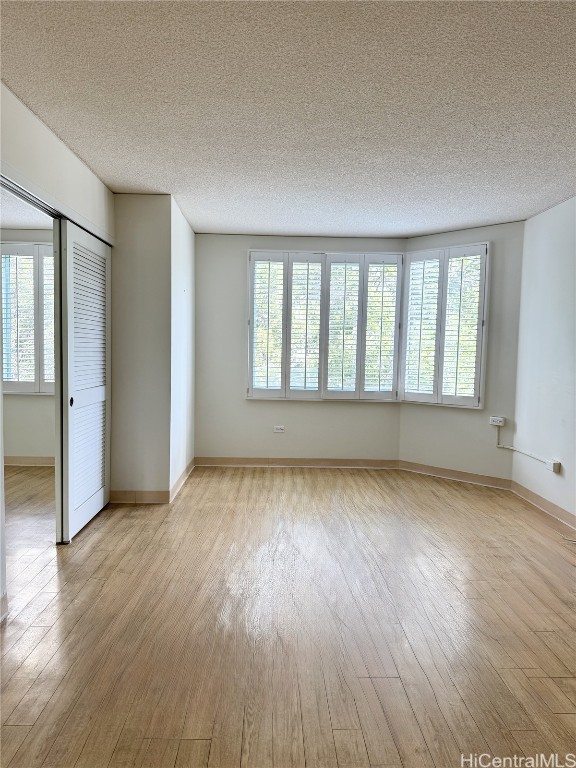 unfurnished room featuring a textured ceiling and light wood-type flooring