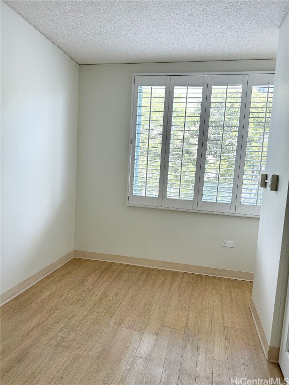 empty room with a textured ceiling and light wood-type flooring