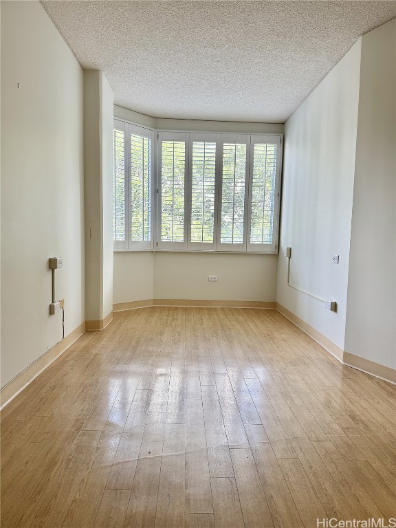 spare room with a textured ceiling and light wood-type flooring