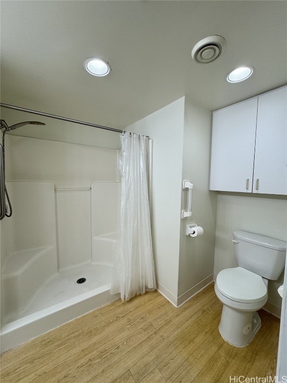 bathroom with curtained shower, toilet, and wood-type flooring