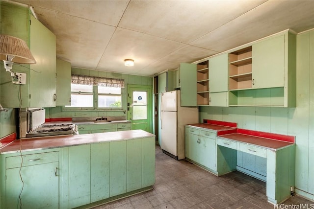 kitchen with white refrigerator, kitchen peninsula, and sink