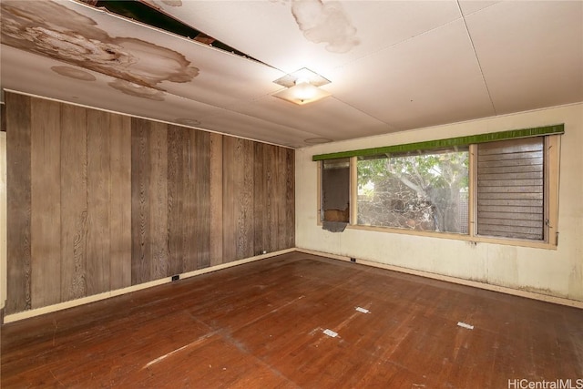 unfurnished room with dark hardwood / wood-style floors and wood walls