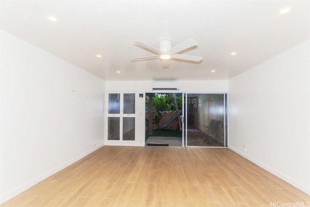 unfurnished room with ceiling fan, light hardwood / wood-style floors, and a wall unit AC