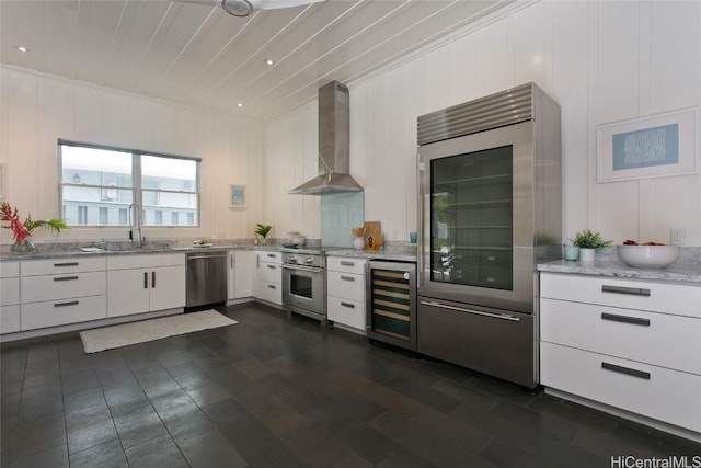 kitchen with white cabinets, sink, wall chimney exhaust hood, appliances with stainless steel finishes, and beverage cooler