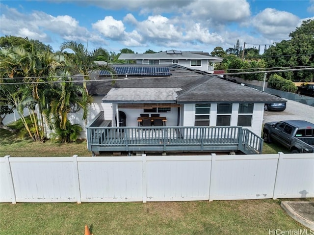 view of front of house with solar panels, a front yard, and a wooden deck