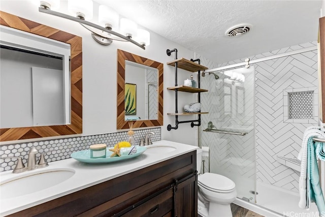 bathroom with vanity, toilet, a textured ceiling, tasteful backsplash, and a shower with shower door