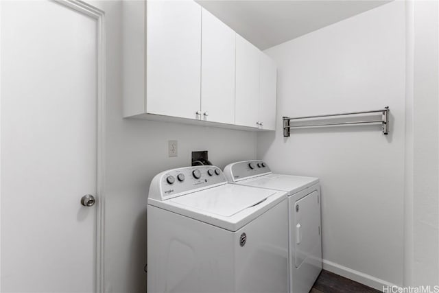 laundry area with dark hardwood / wood-style flooring, washer and clothes dryer, and cabinets