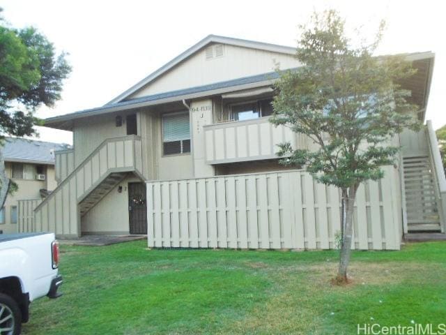 view of front of house with a balcony and a front yard