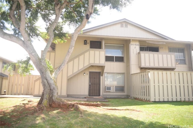 back of house featuring fence, a balcony, and a lawn