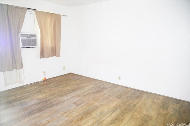 unfurnished room with cooling unit and wood finished floors