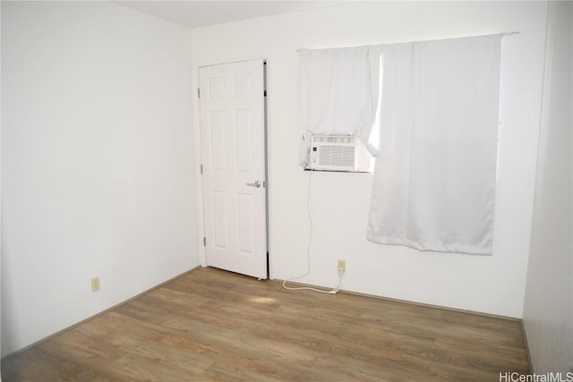 empty room featuring cooling unit and wood finished floors