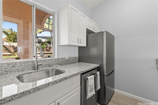 kitchen with dishwasher, sink, white cabinets, and light stone countertops