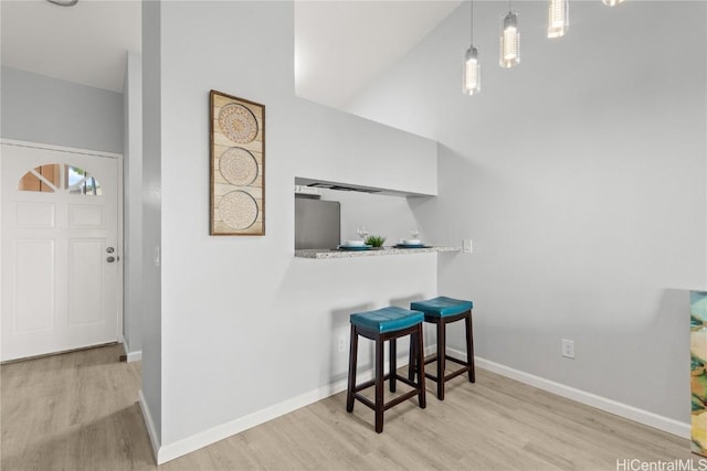 kitchen featuring a breakfast bar, pendant lighting, light hardwood / wood-style flooring, and stainless steel refrigerator