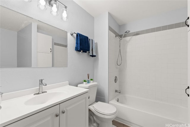 full bathroom featuring tiled shower / bath, vanity, and toilet