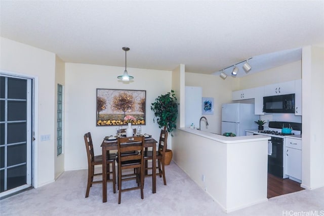 kitchen featuring pendant lighting, white appliances, white cabinets, light colored carpet, and kitchen peninsula