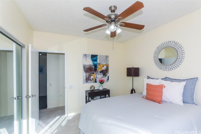 bedroom featuring a closet, a textured ceiling, light colored carpet, and ceiling fan