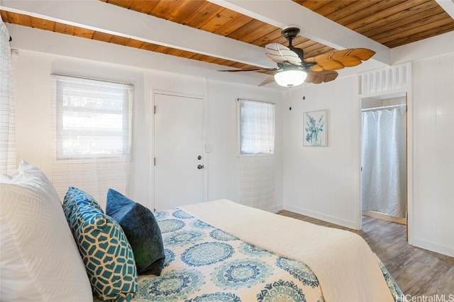 bedroom featuring beamed ceiling, wood-type flooring, multiple windows, and ceiling fan