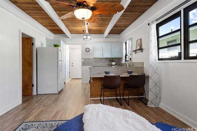 kitchen with tasteful backsplash, a breakfast bar, white fridge, and light hardwood / wood-style floors