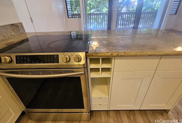 84-754 Ala Mahiku St Unit 52A, Waianae, HI 96792 - kitchen with electric range, light stone countertops, white cabinetry, and light wood-type flooring