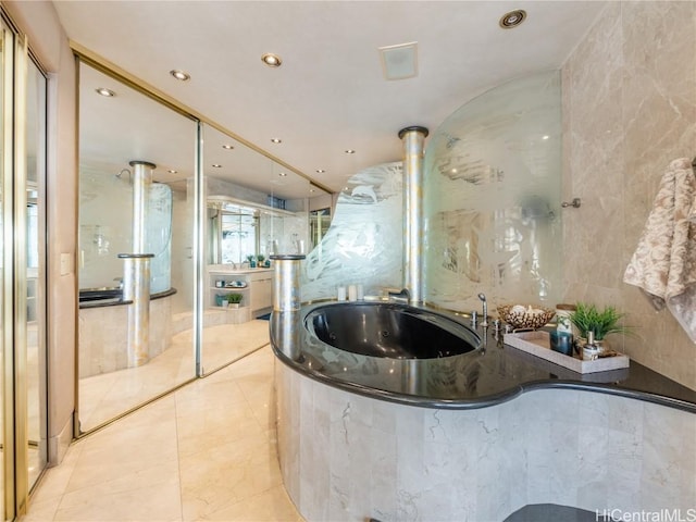 bathroom with a tub to relax in and tile walls