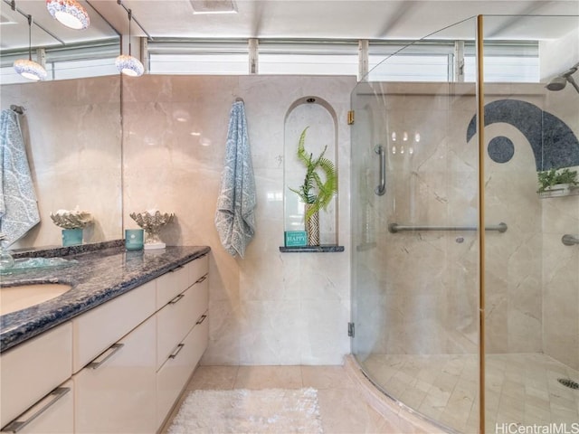 bathroom featuring vanity, a shower with door, and tile walls