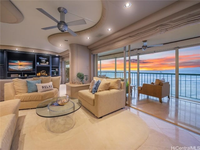 tiled living room featuring ceiling fan and a water view