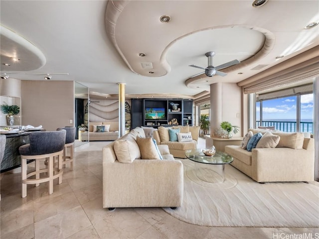 living room with a water view, a raised ceiling, and ceiling fan