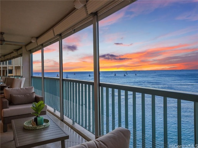 balcony at dusk featuring a water view and an outdoor hangout area