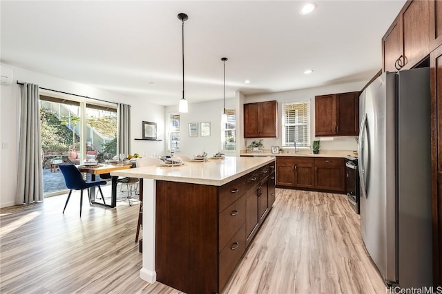 kitchen with pendant lighting, a center island, light hardwood / wood-style flooring, appliances with stainless steel finishes, and a breakfast bar area