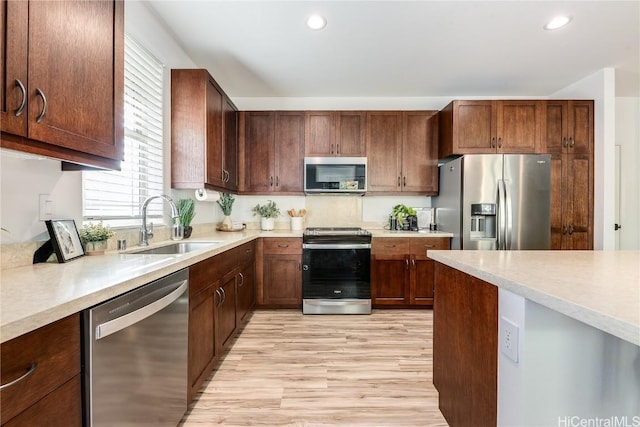 kitchen with appliances with stainless steel finishes, light wood-type flooring, and sink