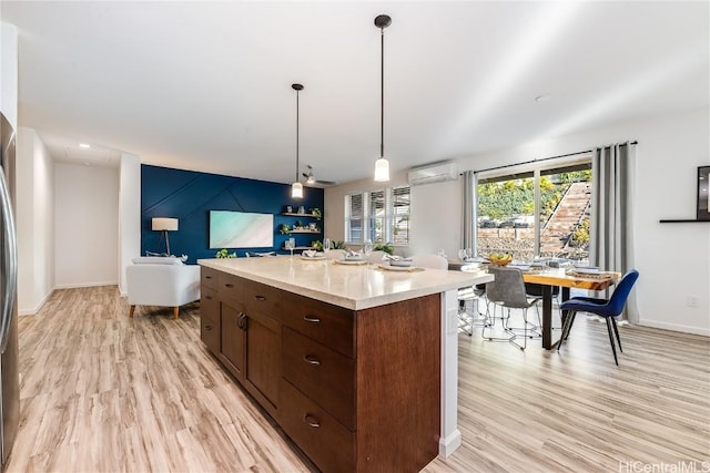 kitchen with pendant lighting, a kitchen island, light hardwood / wood-style floors, and a wall mounted AC