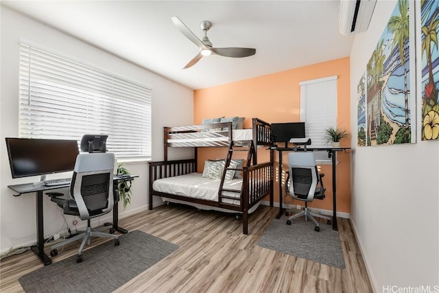 bedroom with ceiling fan, a wall mounted air conditioner, and light wood-type flooring