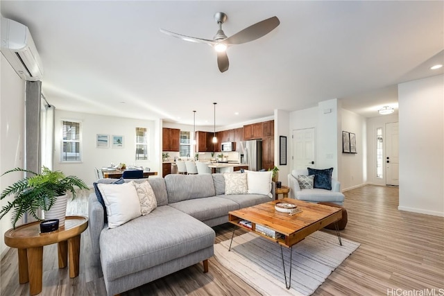 living room featuring a wall unit AC, ceiling fan, and light hardwood / wood-style floors