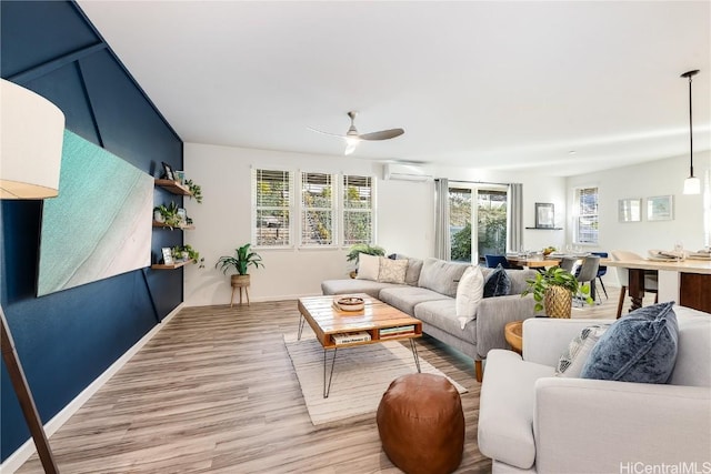 living room with hardwood / wood-style flooring, an AC wall unit, ceiling fan, and a healthy amount of sunlight