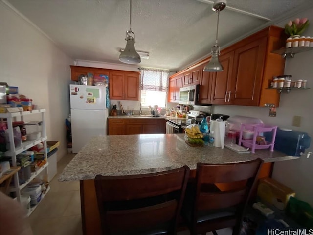 kitchen featuring ornamental molding, appliances with stainless steel finishes, decorative light fixtures, a kitchen bar, and kitchen peninsula