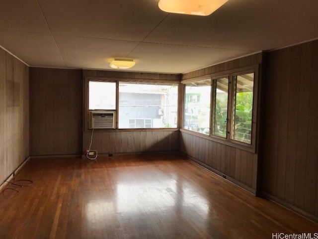 empty room with wood walls, cooling unit, and dark wood-type flooring