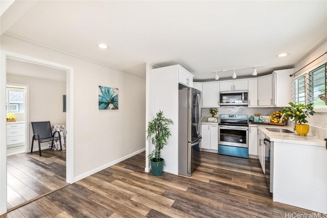 kitchen featuring stainless steel appliances, white cabinetry, backsplash, and dark hardwood / wood-style flooring