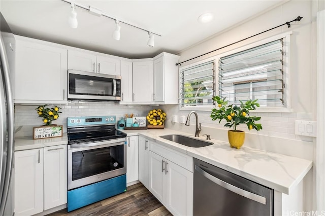 kitchen with light stone countertops, white cabinetry, appliances with stainless steel finishes, and sink