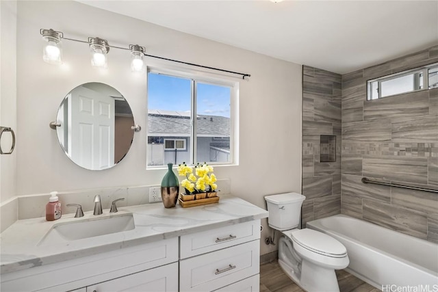 full bathroom featuring hardwood / wood-style floors, vanity, tiled shower / bath, and toilet