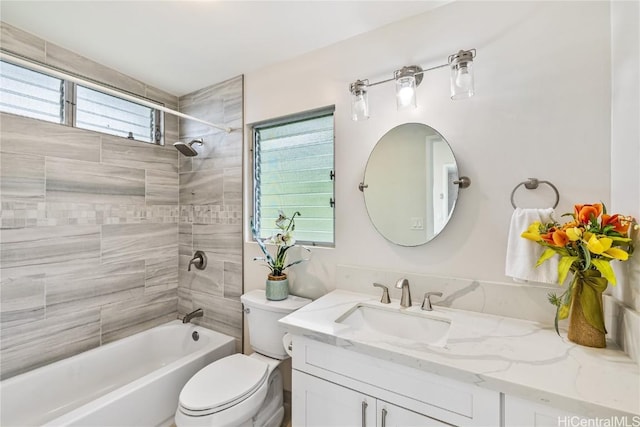 full bathroom with tiled shower / bath, vanity, and toilet